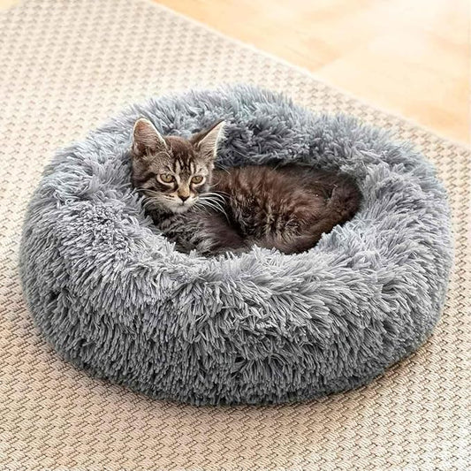 Gato durmiendo plácidamente en cama redonda tipo dona color beige